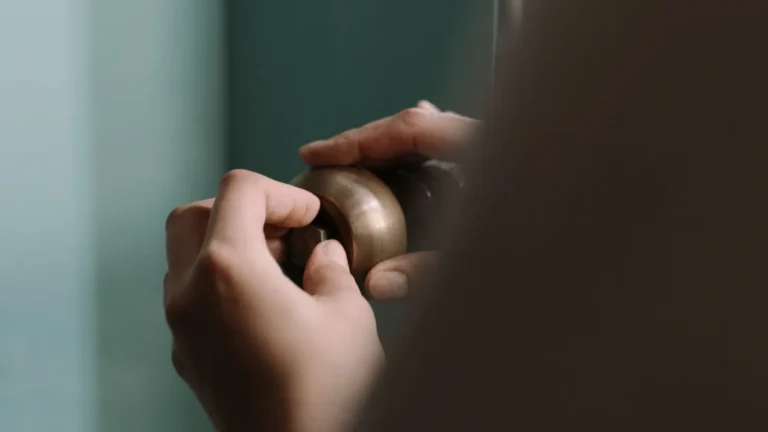 Hands working on a pipe fitting under a kitchen sink